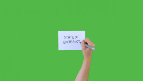 Woman-Writing-State-of-Emergency-on-Paper-with-Green-Screen